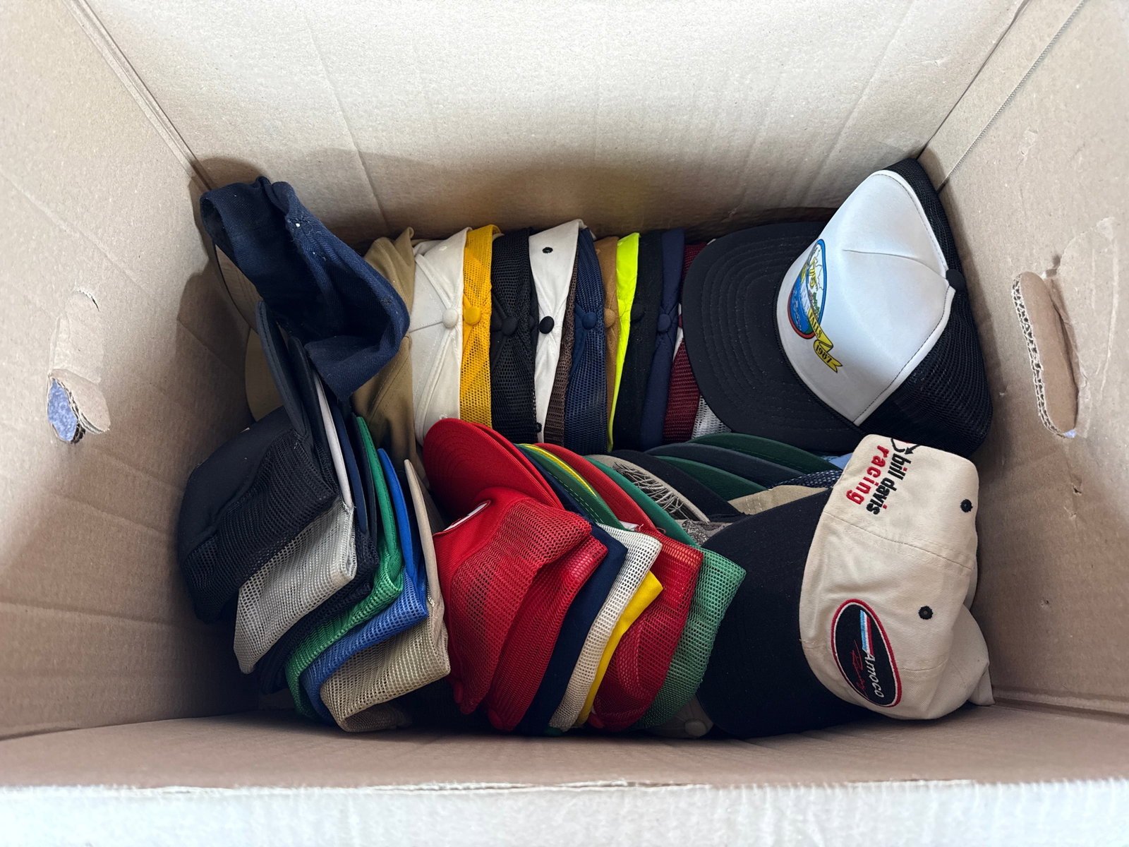 An Assortment of Vintage Advertising and Promotional Trucker Hats: This lot consists of approximately 35 vintage advertising and commemorative baseball caps, primarily designed in the trucker style featuring foam or fabric fronts with mesh back panels and adjustable 