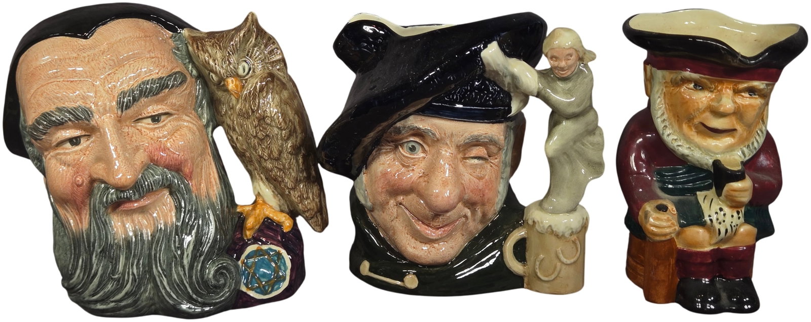 A Trio of Glazed Ceramic Character Jugs Including Royal Doulton Merlin and Tam o' Shanter: This lot comprises glazed ceramic character jugs, featuring pieces by Royal Doulton and one full-bodied jug marked Scottie. The first jug is a Royal Doulton Merlin (D6529), copyrighted in 1959. The pi
