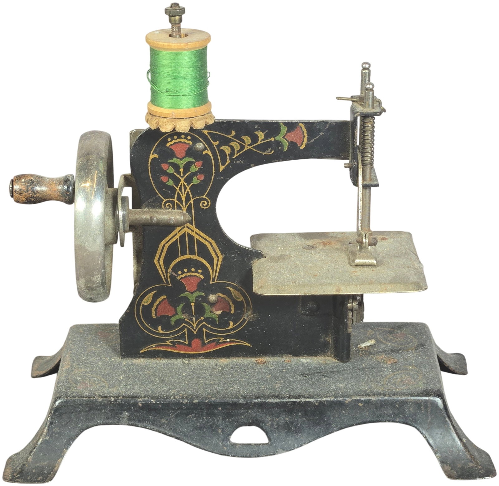 Antique German-Style Miniature Cast Iron Toy Sewing Machine: This antique miniature hand-crank toy sewing machine is constructed with a black-painted cast iron frame and base. The body is decorated with ornate floral and scrollwork decals in red, green, and gol