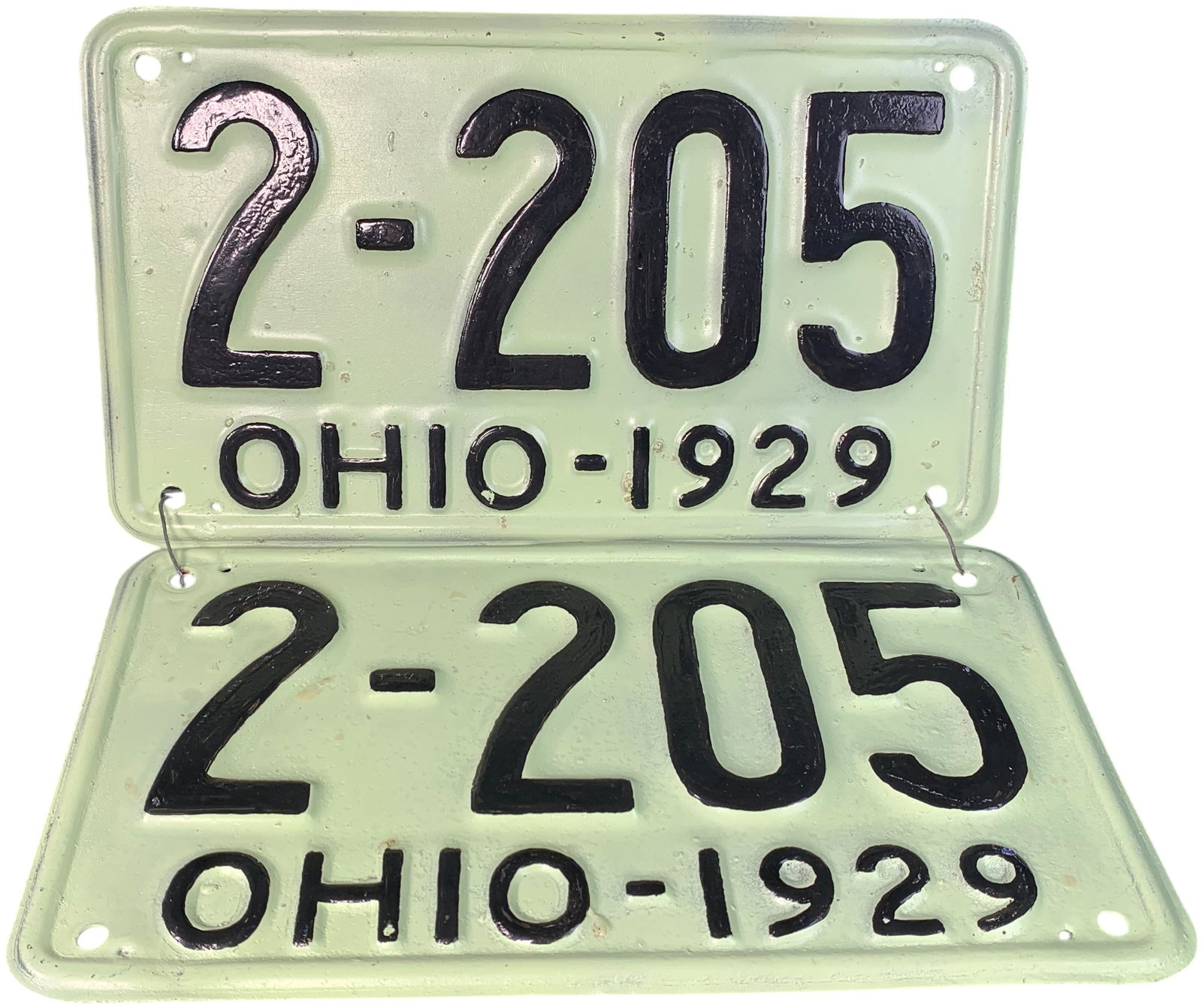 A Pair of Vintage 1929 Ohio Passenger Vehicle License Plates: A matching pair of embossed metal automotive license plates from the state of Ohio, dated 1929. The plates feature a pale mint green background with embossed characters painted in black. The central r