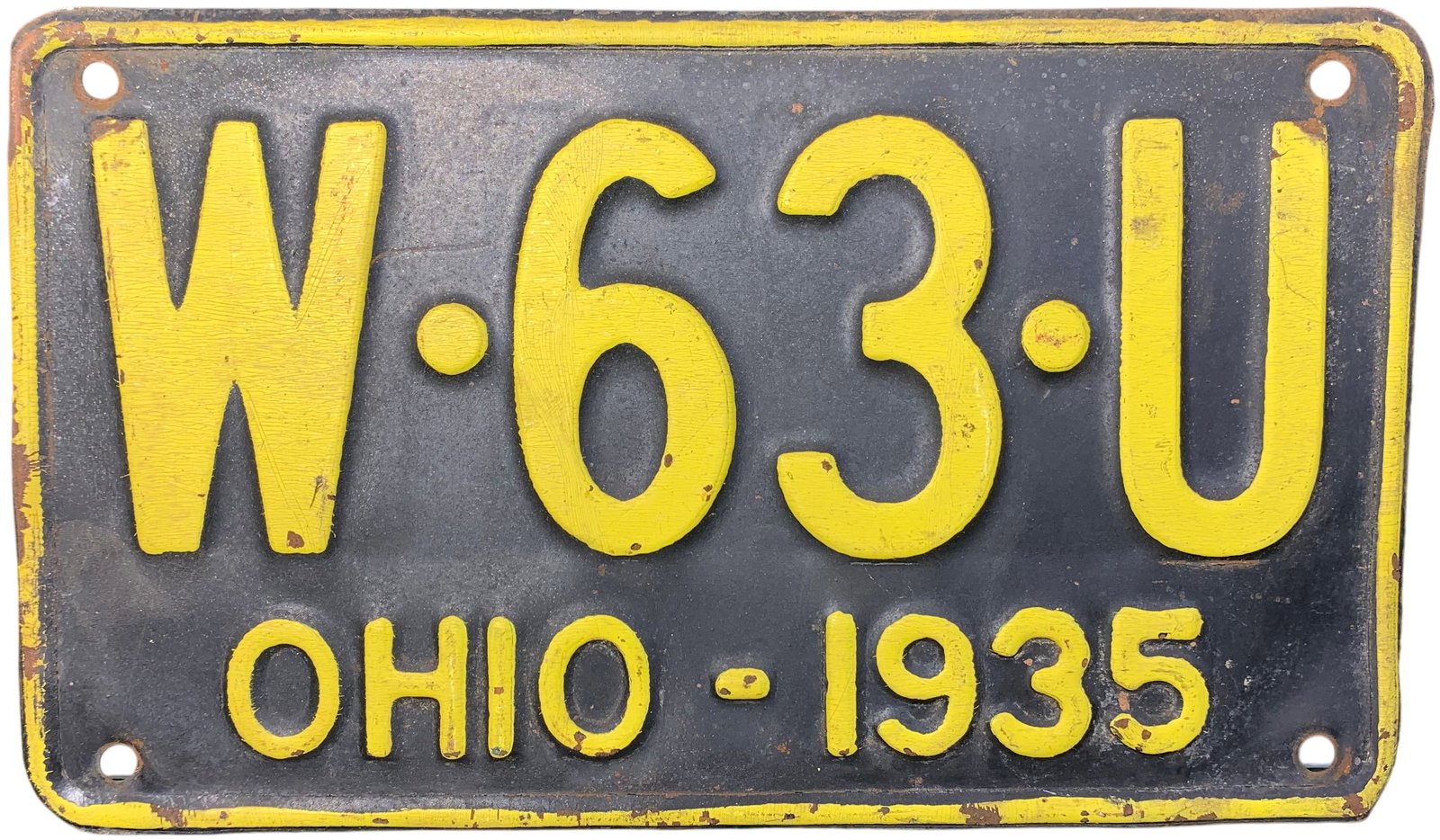 1935 Ohio Metal License Plate, W-63-U: A vintage embossed metal license plate from the state of Ohio, dated 1935. The plate features a dark navy blue background with yellow painted embossed characters. The registration number W·63·U is c