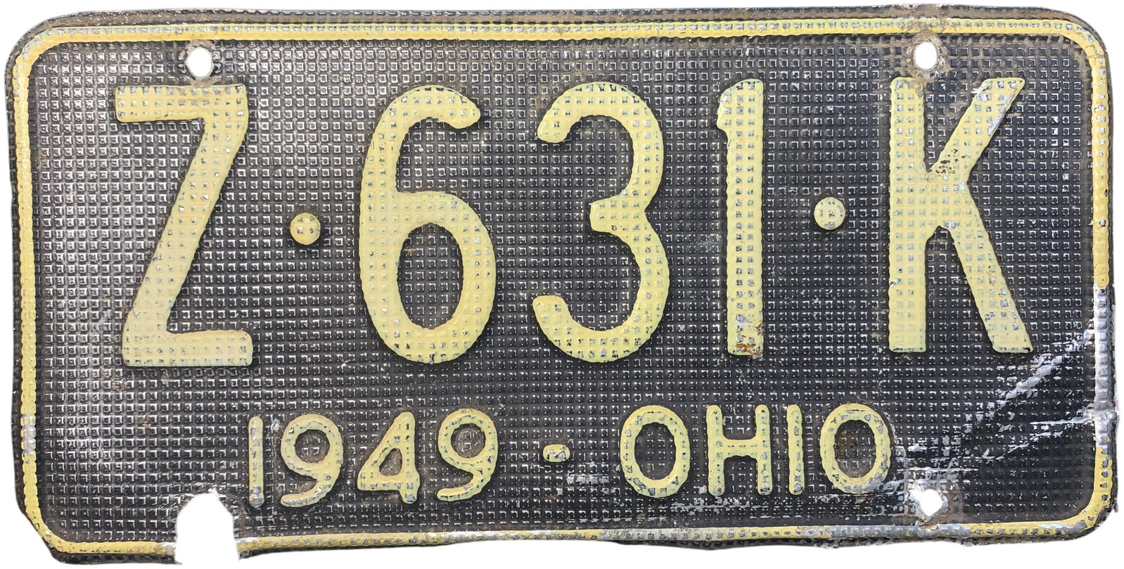 1949 Ohio Waffle Texture Passenger License Plate: A vintage 1949 Ohio passenger vehicle license plate featuring a distinctive embossed waffle or grid-textured background. The plate is constructed of metal with a dark background field and contrasting 