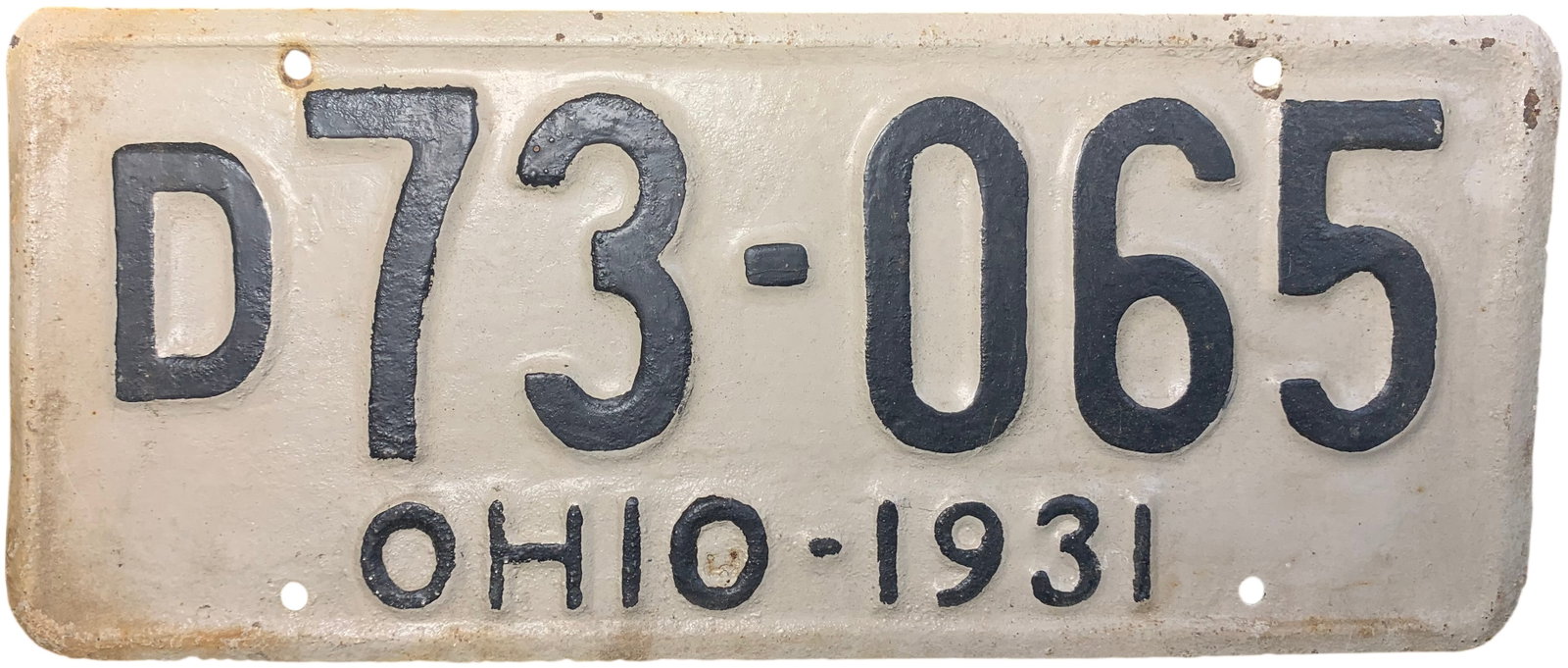 1931 Ohio Passenger License Plate Serial D73-065: A 1931 Ohio state-issued passenger license plate. This embossed steel plate features a cream background with dark embossed characters. The central serial number is D73-065. The lower portion of the pl