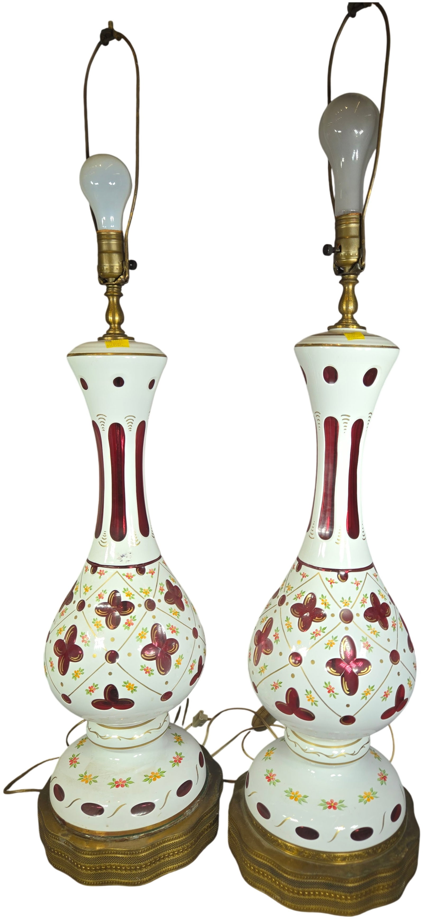 A Pair of Tall Bohemian White Cut-to-Cranberry Cased Glass Table Lamps: This matching pair of table lamps is constructed from white-to-cranberry cased glass, a style characteristic of Bohemian glass production. The glass bodies feature intricate cut-to-clear decoration, i