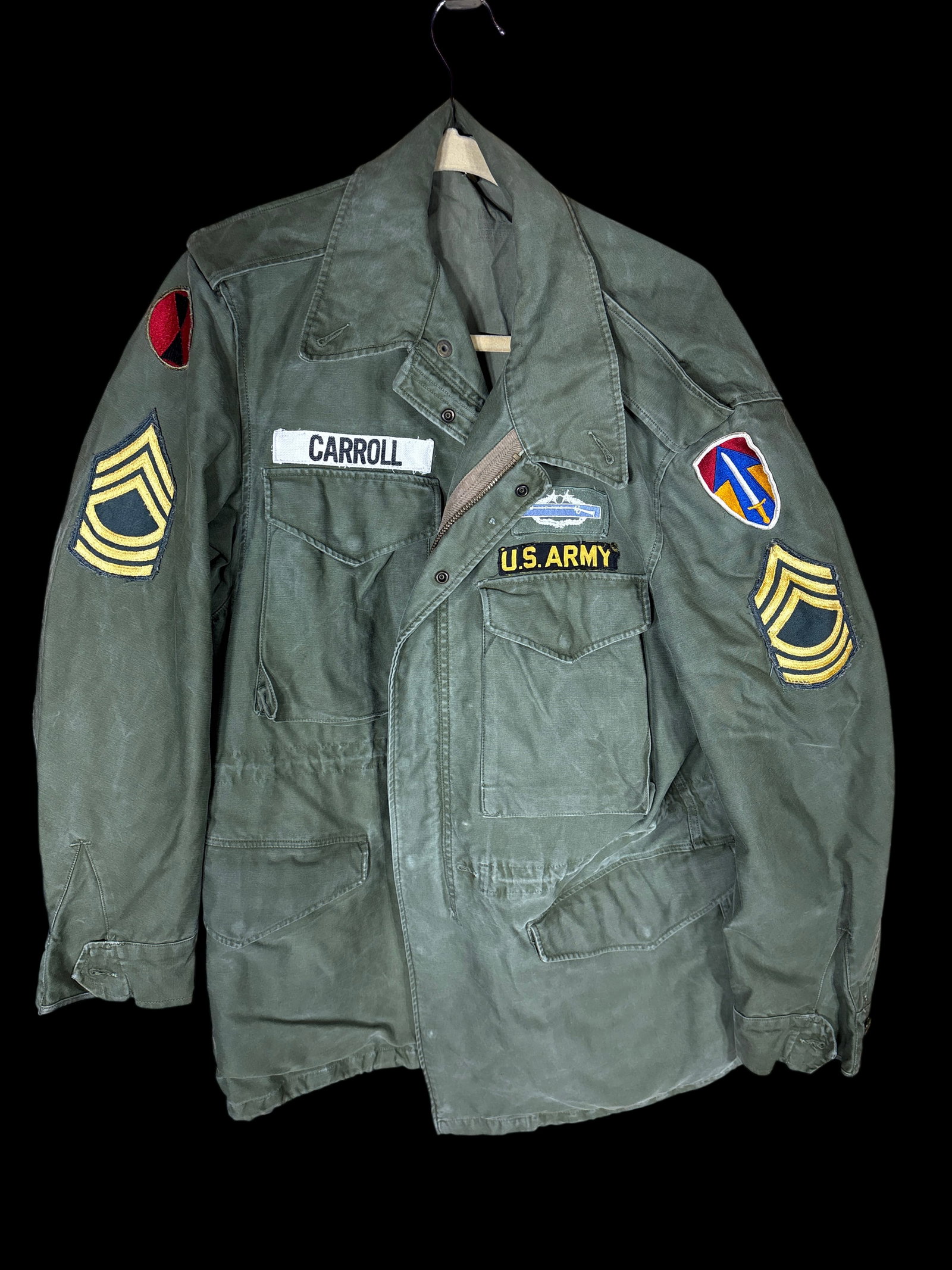 US Army Vietnam Era M-1951 Field Jacket with 1st Infantry Division and USARV Patches: This United States Army M-1951 field jacket is constructed from OG-107 olive green cotton sateen. The garment features a heavy-duty metal front zipper with a button-down storm flap, four front cargo p