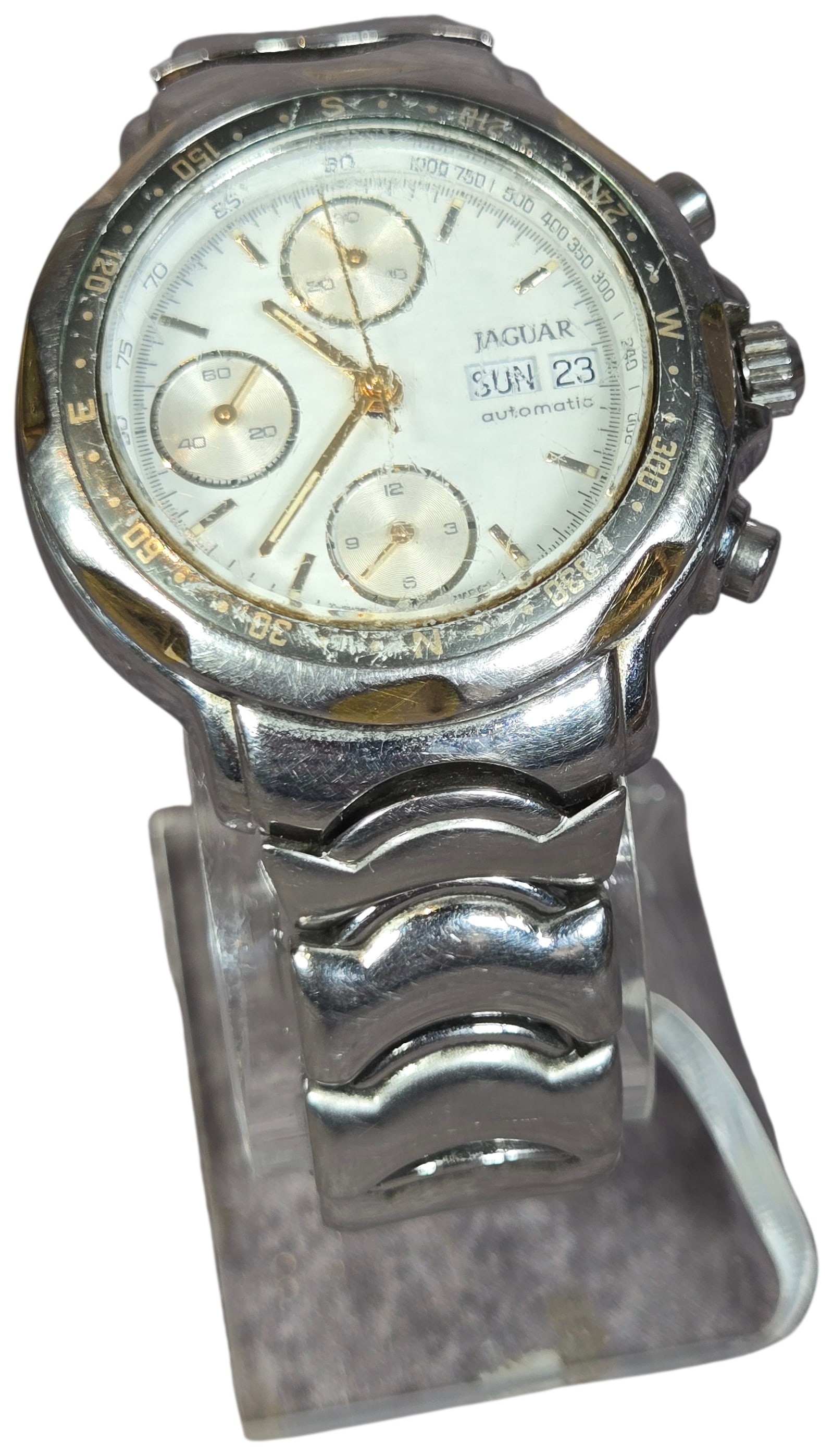 Jaguar Automatic Chronograph Wristwatch Reference J910: A men's Jaguar automatic chronograph wristwatch, reference number J910. The watch features a stainless steel case with gold-tone accents on the bezel, crown, and chronograph pushers. The white dial is