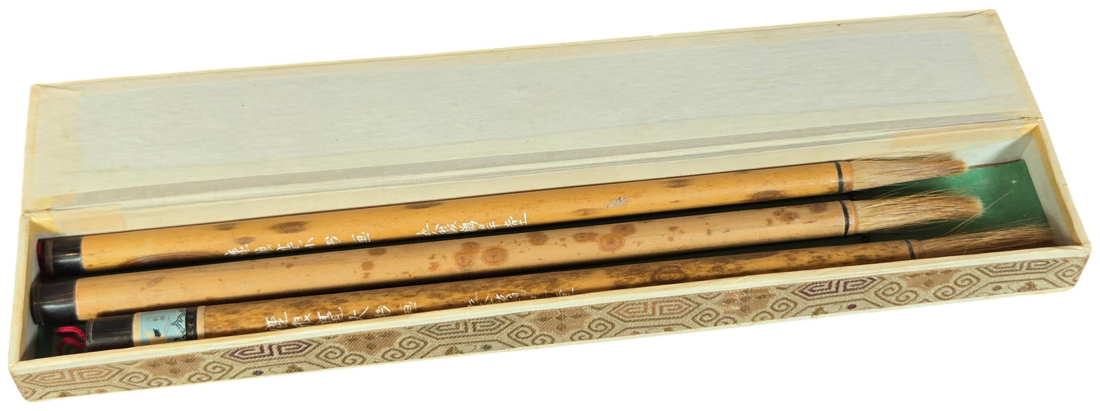 Trio of Chinese Calligraphy Brushes by An Jin Wei in Fitted Box: A set of three Chinese calligraphy brushes manufactured by An Jin Wei. The brush handles are constructed from mottled bamboo, characterized by its naturally occurring dark spots. Each brush is inscrib