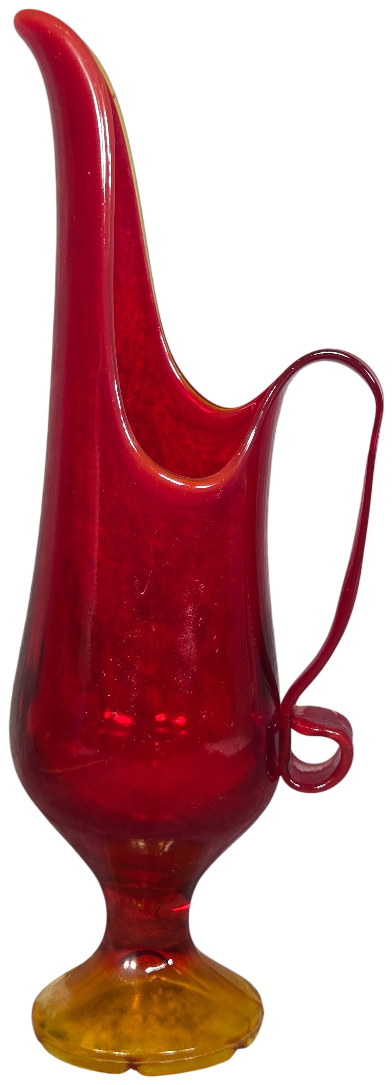 L.E. Smith Amberina Art Glass Pulled Spout Pitcher: This hand-blown art glass pitcher by L.E. Smith features an Amberina colorway, displaying a gradient that transitions from a deep ruby red at the rim to a vibrant amber-orange at the base. The vessel 