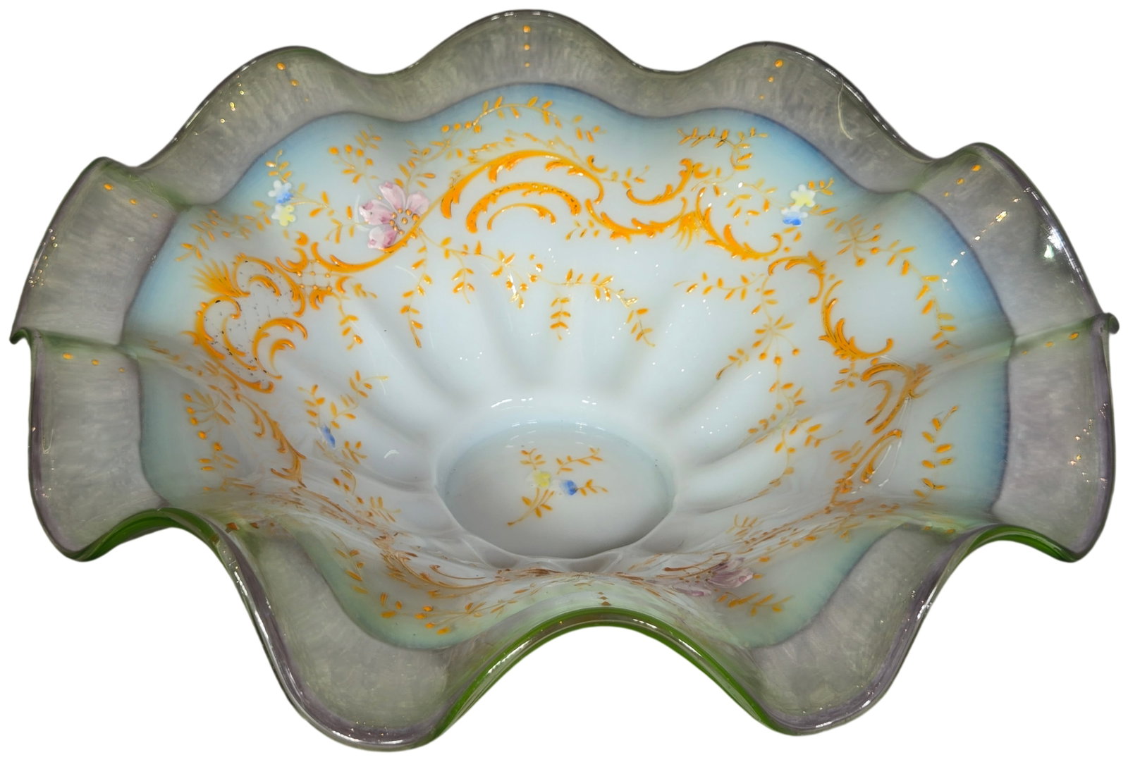 Victorian Uranium Opalescent Glass Bride's Bowl with Hand Enameled Floral Decoration: This large Victorian art glass bride's bowl is crafted from opalescent glass. It features a translucent white-to-blue core that transitions to a transparent, pale green rim. The green portion of the g