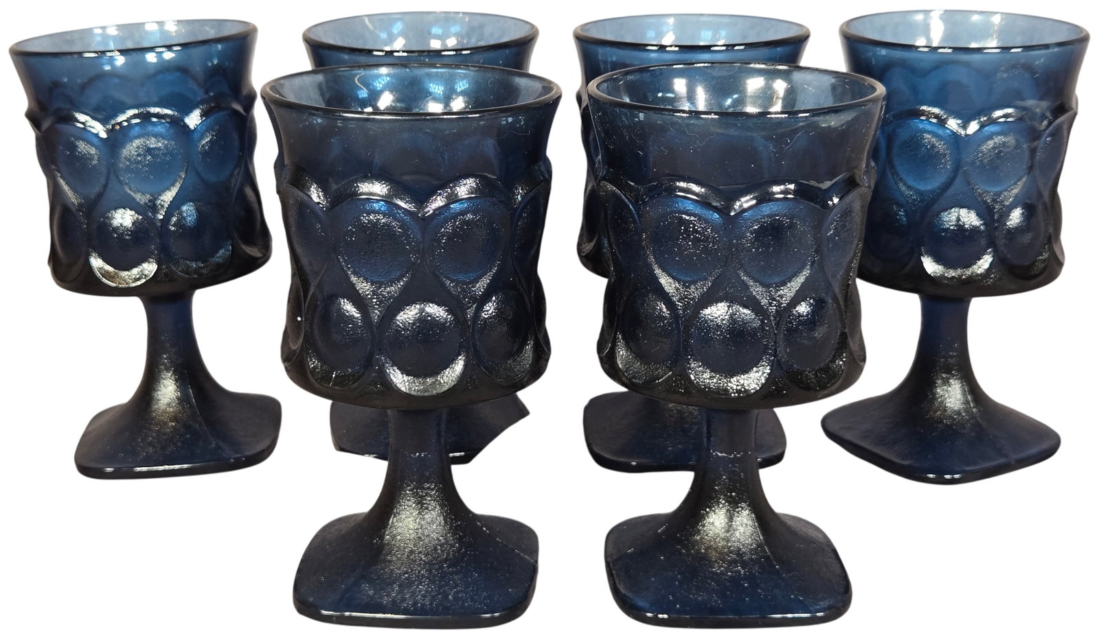 Set of Six Noritake Spotlight Blue Glass Wine Goblets: A set of six pressed glass wine goblets in the Spotlight pattern by Noritake, produced in a deep cobalt blue color. Each goblet features a flared rim and a cylindrical bowl decorated with a repeating 