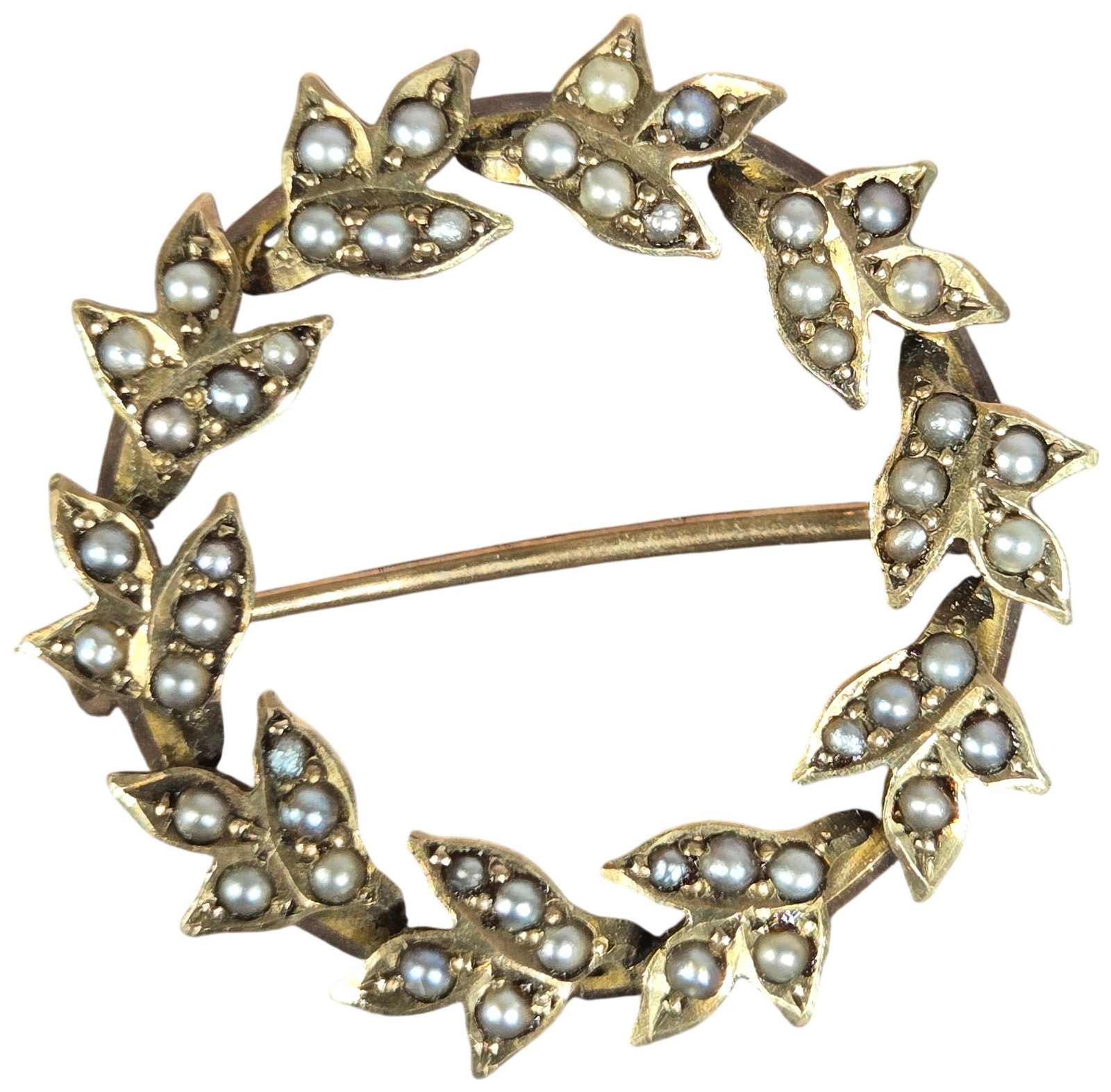 Antique 10 Karat Yellow Gold and Seed Pearl Wreath Brooch: This antique wreath brooch is crafted in 10 karat yellow gold and features a circular frame decorated with twelve foliate clusters. Each cluster is composed of three leaves, with each individual leaf 