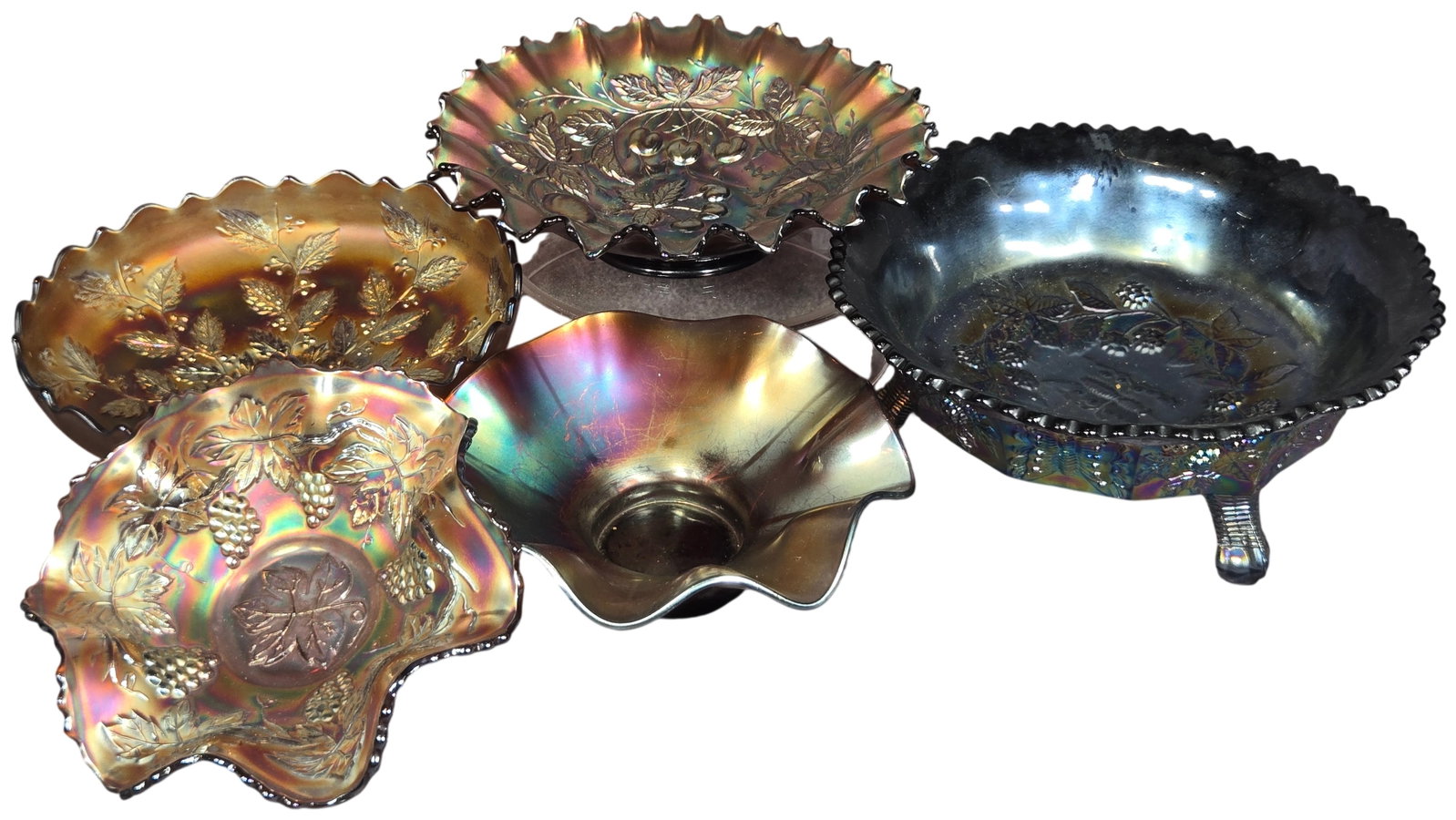 A Collection of Imperial and Fenton Carnival Glass Bowls in Various Patterns: This group consists of several pieces of American iridescent pressed glass featuring various traditional patterns. Included is an Imperial Fruit bowl with molded pears, cherries, and grapes, finished 