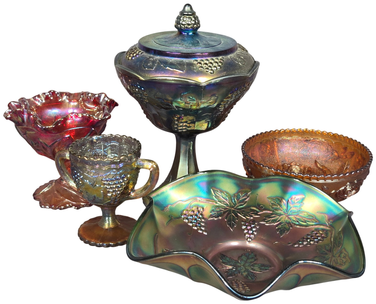 A Collection of American Iridescent Carnival Glass Tableware Including Indiana Glass Harvest Grape: This collection consists of five pieces of pressed carnival glass featuring iridescent finishes and various botanical relief patterns. The group includes one green ruffled bowl in the Grape and Cable 