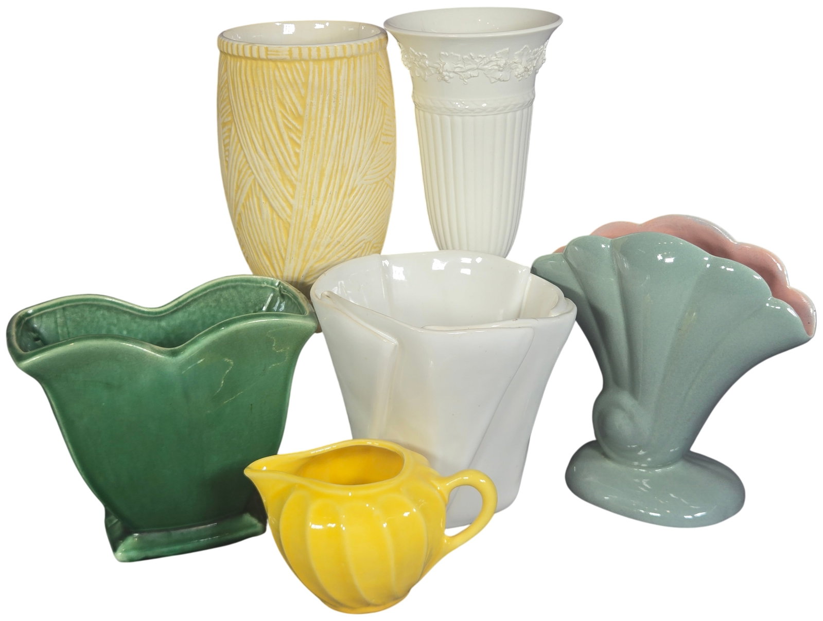 An Assortment of Six Ceramic Vases and a Creamer Including Wedgwood and McCoy: An assortment of six decorative ceramic items including vases and a creamer from several manufacturers. The group features a Wedgwood Embossed Queensware trumpet-shaped pedestal vase in creamware eart