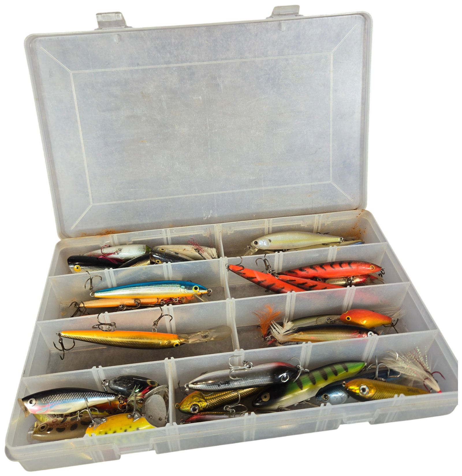 An Assortment of Vintage and Modern Fishing Lures in a Plano Hydro-Flo Stowaway Tackle Box: This collection consists of an assortment of hard fishing lures, including jerkbaits, crankbaits, and topwater models, presented in a Plano Hydro-Flo Stowaway clear plastic utility box. The lures are 