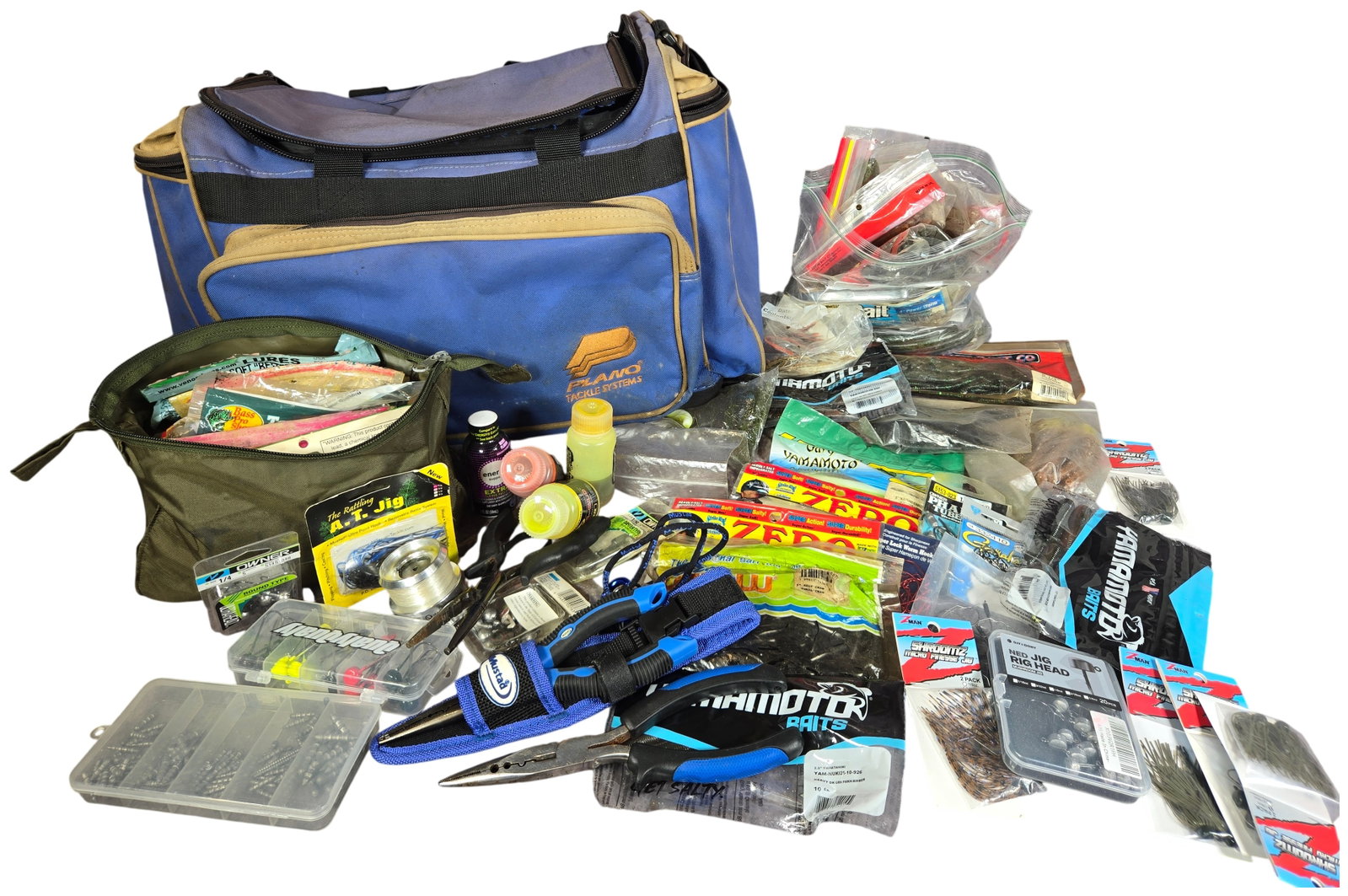 An Assortment of Freshwater Bass Fishing Tackle and Accessories with Plano Soft-Sided Bag: A collection of freshwater bass fishing gear featuring a Plano Tackle Systems soft-sided bag in blue and tan. The assortment includes numerous soft plastic lures in both factory-sealed and opened pack