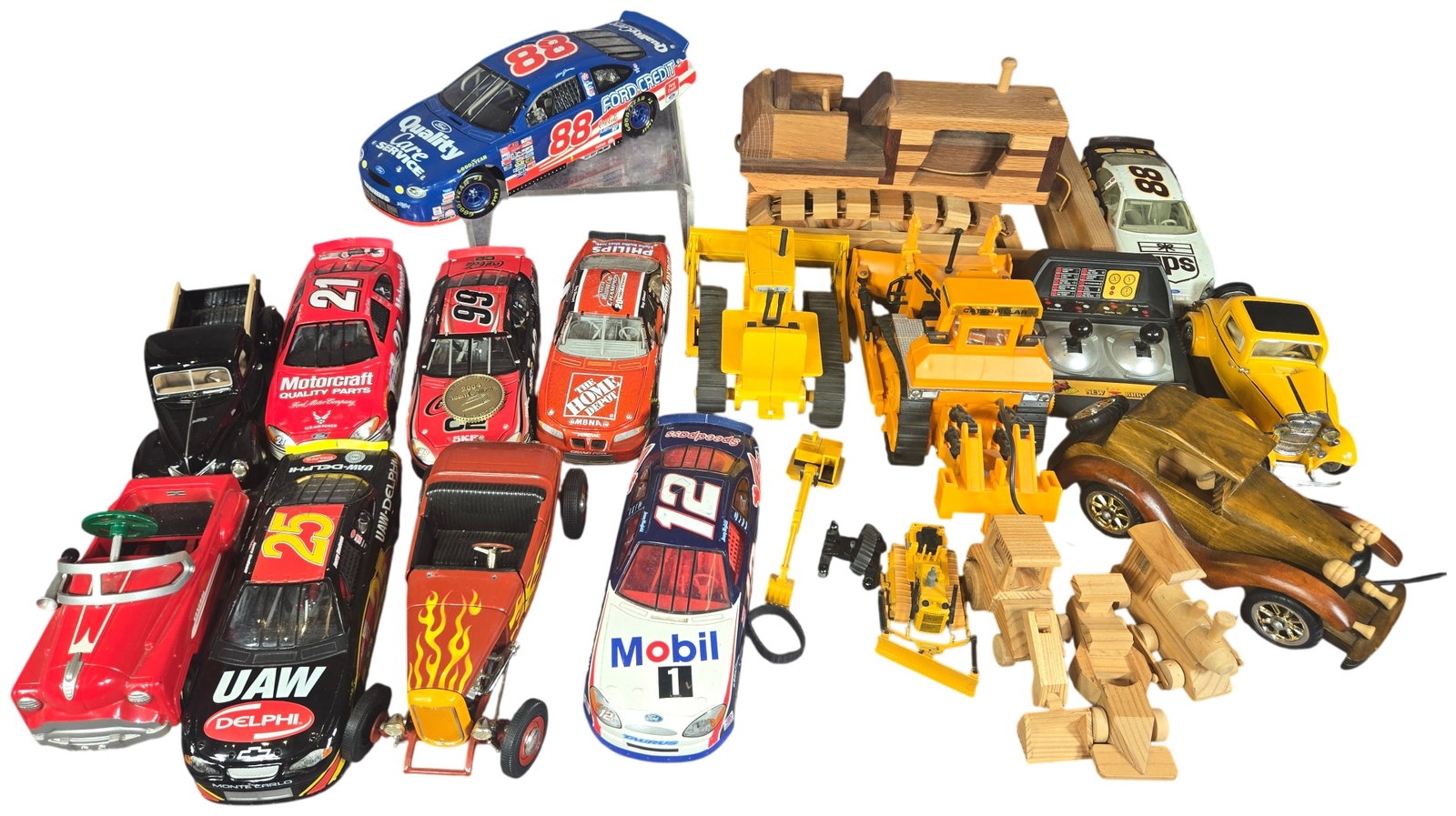 An Assortment of Die-Cast NASCAR Vehicles, Classic Cars, and Wooden Toys: This collection features a variety of toy vehicles, including 1:24 scale NASCAR die-cast cars, vintage automobile models, and wooden toys. The NASCAR selection includes several Ford Taurus models, suc