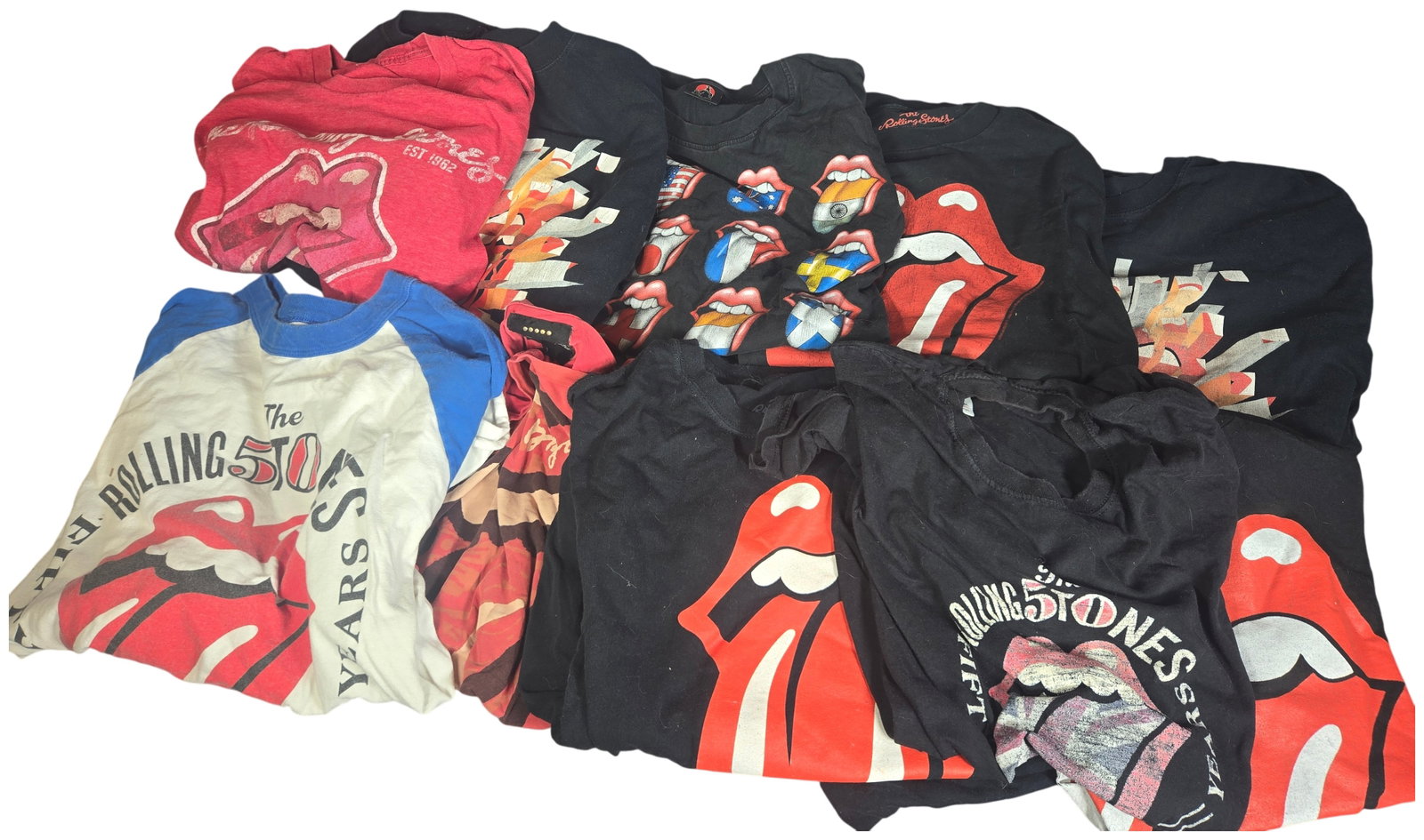 A Collection of Rolling Stones Graphic Apparel Including A Bigger Bang Tour and Fifty Years: A collection of approximately ten items of graphic apparel featuring branding for the English rock band, The Rolling Stones. The lot comprises a mix of official concert tour merchandise, commemorative