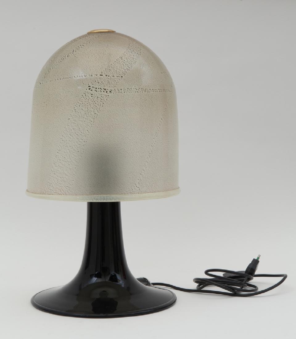 VENINI (Editore) Una lampada da tavolo, anni: VENINI (Editore) Una lampada da tavolo, anni '60. Basamento in vetro nero, diffusore in vetro opalescente con applicazione di foglia d'argento, ottone. Altezza cm 55. Letteratura: Franco Deboni, I vet