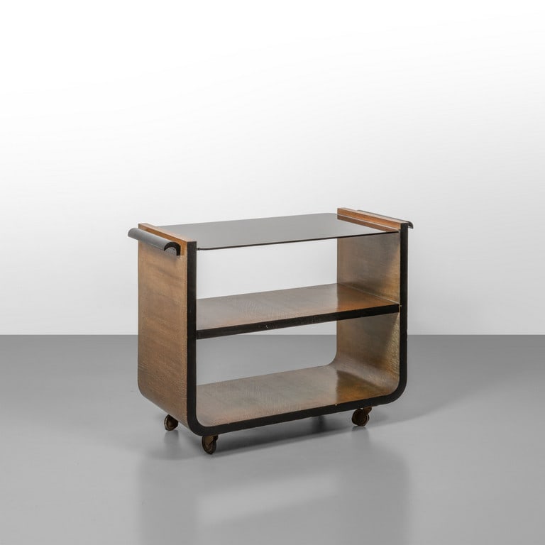 UN CARRELLO, anni '30. Legno di rovere in: UN CARRELLO, anni '30. Legno di rovere in parte ebanizzato, vetro opale nero, ruote. Cm 69 (h) x 90 (l) x 46 (p).