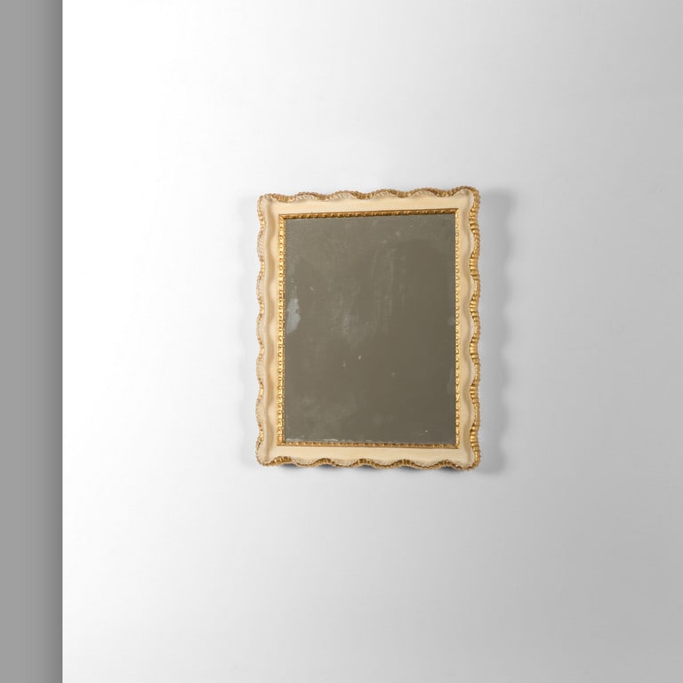 UN PICCOLO SPECCHIO DA PARETE, anni '50. Legno: UN PICCOLO SPECCHIO DA PARETE, anni '50. Legno intagliato decorato a foglia oro, finitura in gesso, cristallo argentato. Cm 35 (h) x 30.