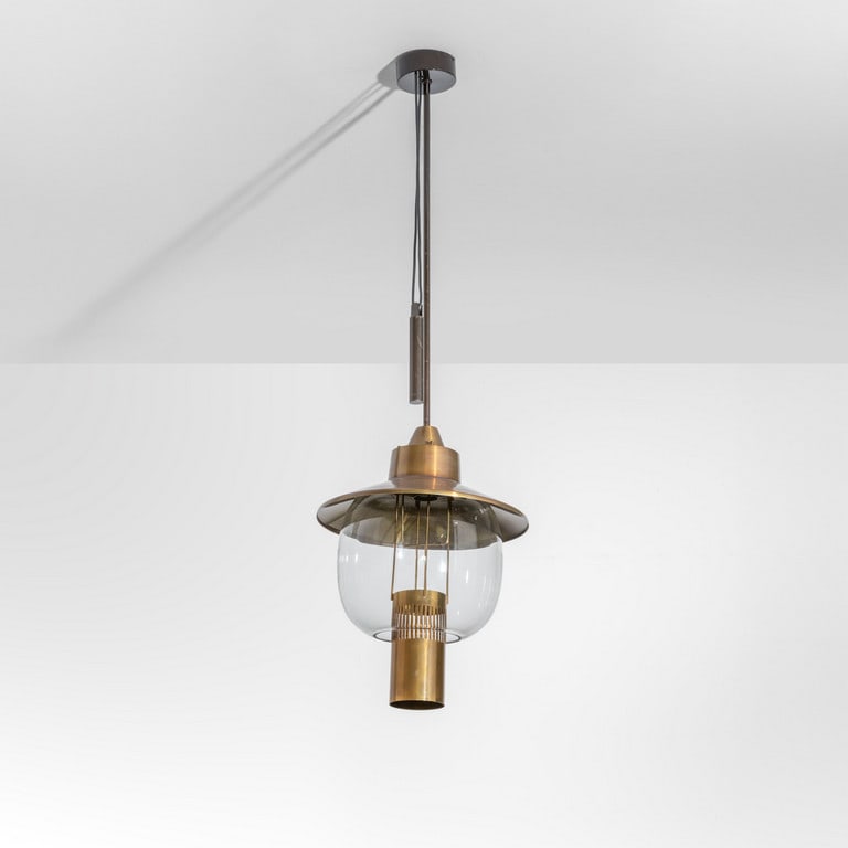 LUMIERE (Editore), anni '60. Una lampada a: LUMIERE (Editore), anni '60. Una lampada a sospensione con saliscendi per corpo portalampada. Ottone, alluminio anodizzato, metallo verniciato, vetro. Etichetta della Manifattura. Cm 130 (h. diffusore