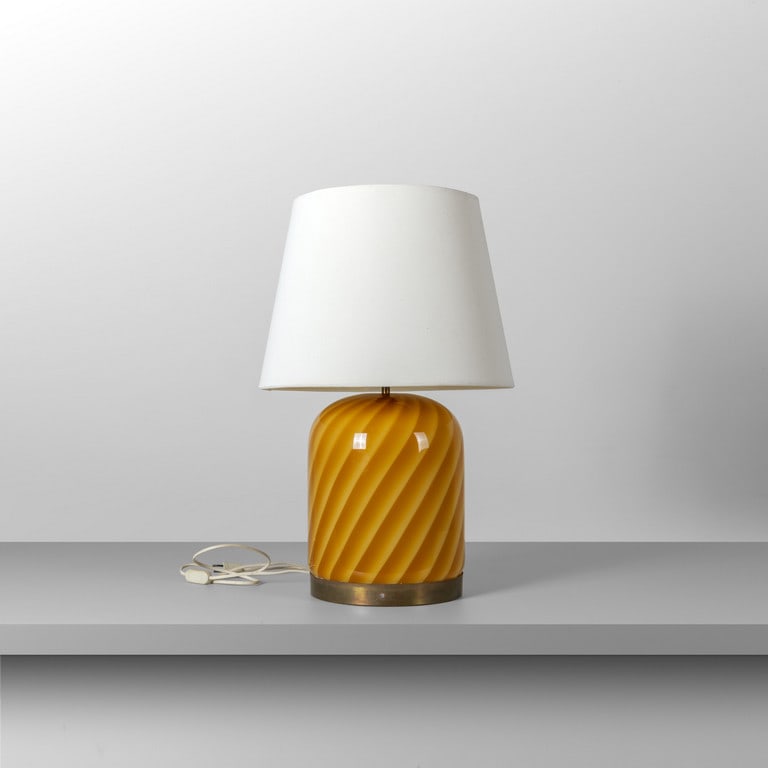 TOMMASO BARBI, anni '70. Una lampada da: TOMMASO BARBI, anni '70. Una lampada da tavolo. Vetro, ottone, paralume in tessuto plastificato. Etichetta della Manifattura. Cm 67 (h).