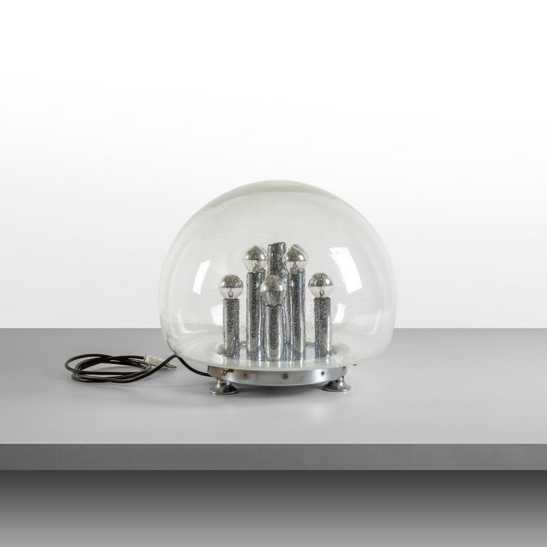 MURANO, anni '70. Una lampada da: MURANO, anni '70. Una lampada da tavolo. Acciaio cromato, vetro con applicazioni di graniglie. Cm 37 (h) x 45 (diam.).