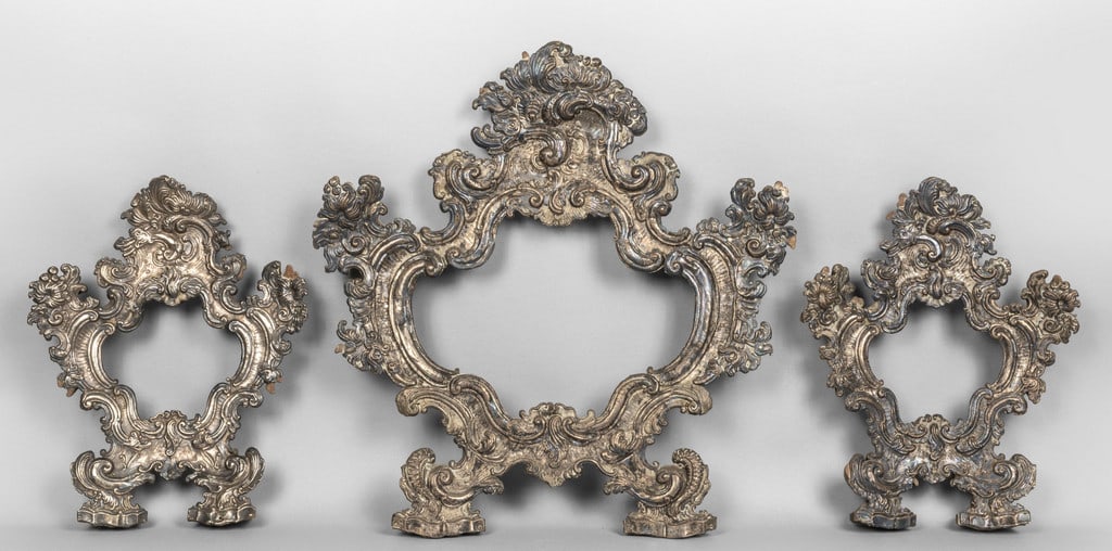 Trittico di cantaglorie in argento finemente: Trittico di cantaglorie in argento finemente sbalzato con ricca decorazione a motivi floreali e pellacce, Lombardia sec.XVIII la grande cm.50x47, le piccole cm.36x28