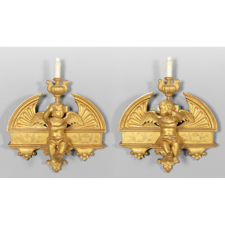 Coppia di apliques in legno intagliato e dorato a: Coppia di apliques in legno intagliato e dorato a una luce con angioletti, sec.XIX cm. 50x45
