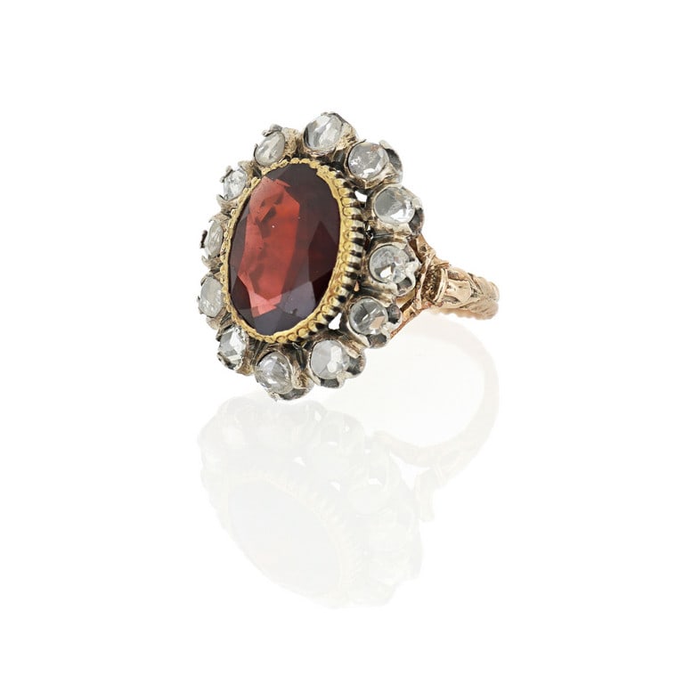 Anello in oro rosso e argento, la foggia floreale: Anello in oro rosso e argento, la foggia floreale è realizzata con un granato ovale al centro, contornato da piccoli diamanti taglio rosa. Misura n. 15. Peso 12,0 g.