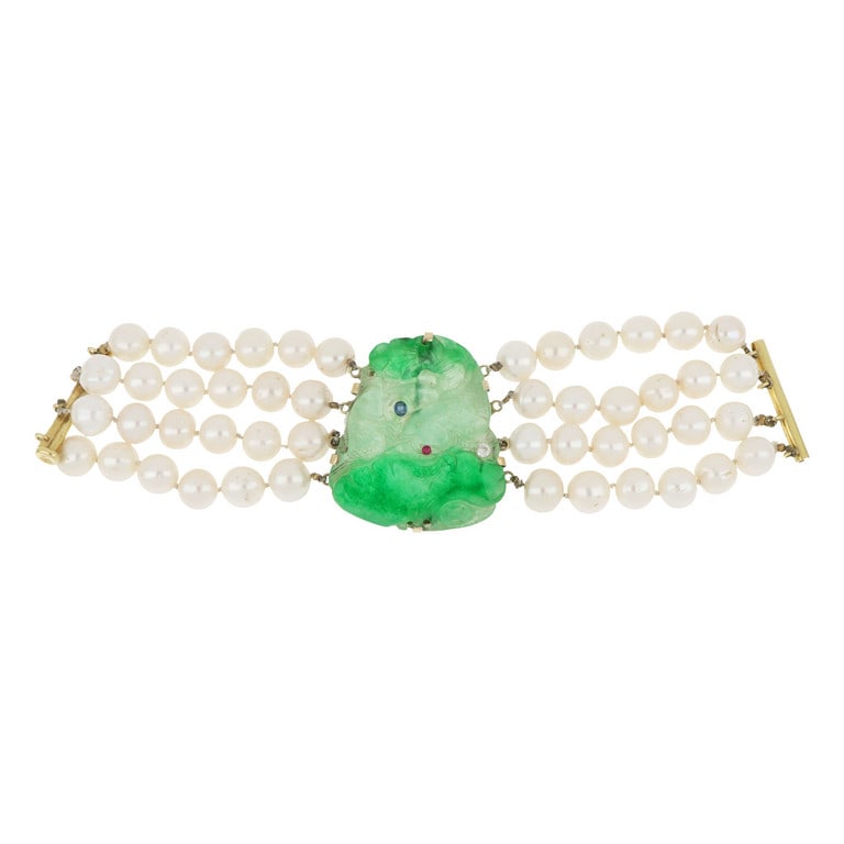 Bracciale a quattro fili di perle coltivate e: Bracciale a quattro fili di perle coltivate e grande placca di giadeite centrale ed incisa con il motivo dei pesci. Chiusura a baionetta in oro. Lunghezza 20 cm. Peso 126,12 g.