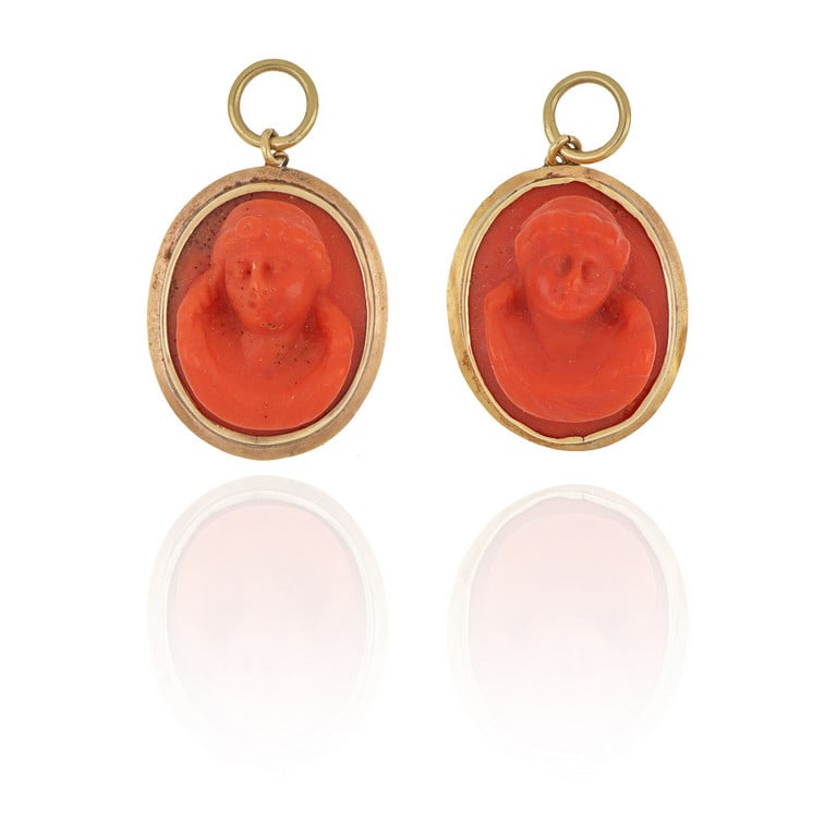 Coppia di ciondoli in oro e corallo rosso: Coppia di ciondoli in oro e corallo rosso aranciato raffiguranti miniature di busti in altorilievo. Peso 8,65 g.