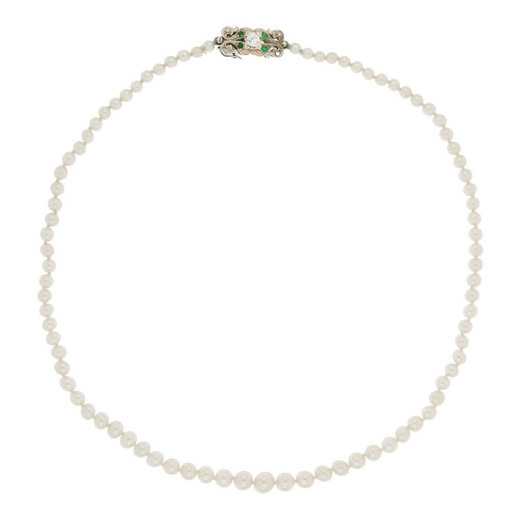 Collana di perle giapponesi coltivate scalari, da: Collana di perle giapponesi coltivate scalari, da 4 a 7,75 mm, chiusa da una fermezza in oro bianco rettangolare, al centro un diamante di taglio antico di ct. 0,40 ca., piccoli smeraldi e diamanti. L