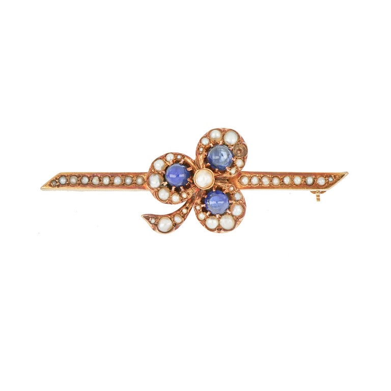 Spilla d'epoca in oro rosso a forma di trifoglio: Spilla d'epoca in oro rosso a forma di trifoglio con piccole perline e zaffiri cabochon. Lunghezza 57 mm. Peso 8,74 g.