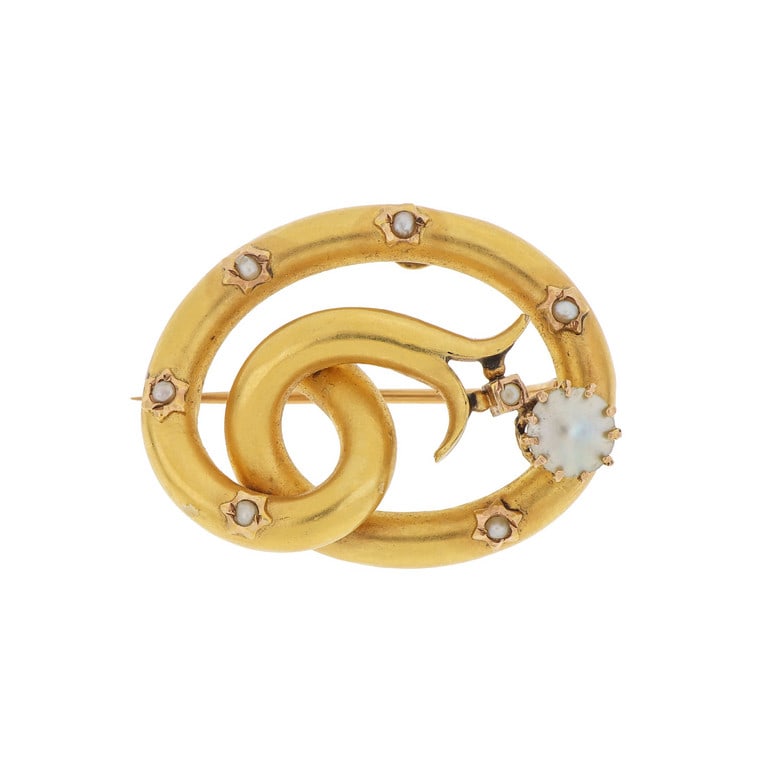 Spilla a cornucopia, in oro giallo finemente: Spilla a cornucopia, in oro giallo finemente coppellato e decorato con piccole perline. Dimensioni 3,5 x 3 cm. Peso 5,83 g.