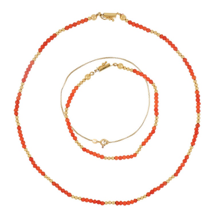 Set in oro giallo e corallo, composto da una: Set in oro giallo e corallo, composto da una collana e un braccialetto, entrambi realizzati con piccole boule intercalate a sferette di corallo arancione. Si aggiunge un braccialetto a fine catenina i