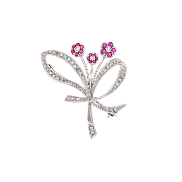 Spilla in oro bianco a mazzolino di fiori,: Spilla in oro bianco a mazzolino di fiori, decorata con piccoli diamanti sugli steli e rubini sui petali. Dimensioni 5 x 4 cm. Peso 8,95 g.