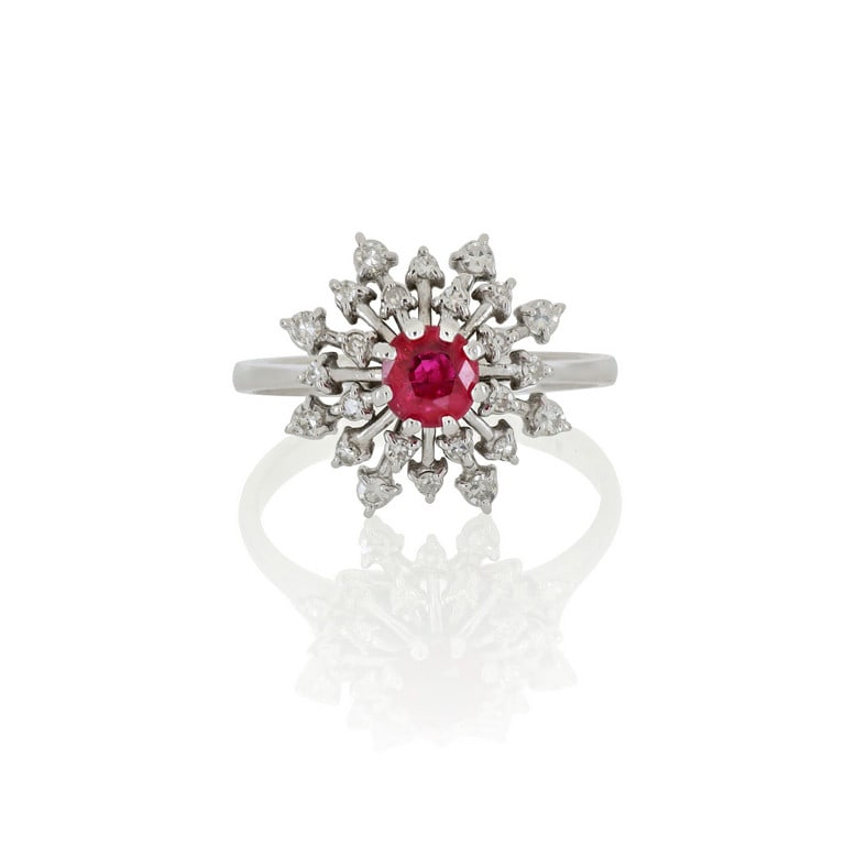 Anello in oro bianco a forma di fiocco di neve,: Anello in oro bianco a forma di fiocco di neve, al centro un rubino rosso vivace, taglio rotondo, ct. 0,40 ca., piccoli brillanti decorano tutto il gioiello. Misura n. 14. Peso 4,62 g.