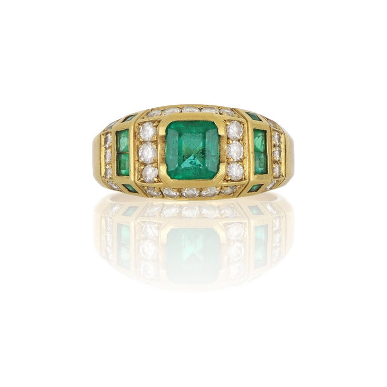Anello in oro giallo a fascia squadrata, al: Anello in oro giallo a fascia squadrata, al centro uno smeraldo taglio carrè di ct. 0,60 ca. ai lati piccoli diamanti taglio brillante e smeraldini carrè. Misura n. 11. Peso 7,44 g.