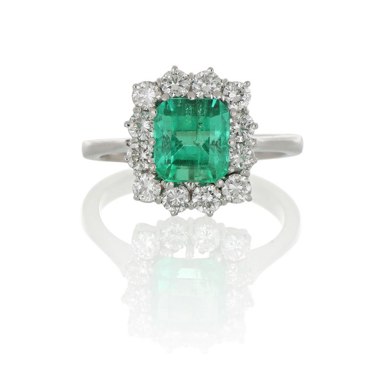 Classico anello a margherita, realizzato in oro: Classico anello a margherita, realizzato in oro bianco, al centro un luminoso smeraldo colombiano di ct. 1,70 ca., 12 diamanti taglio brillante contornano la gemma, per ct. 0,90 ca. Misura n. 10. Peso
