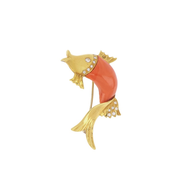 Spilla in oro giallo "Animalier", un gioioso: Spilla in oro giallo "Animalier", un gioioso pesciolino salta fuori dall'acqua, realizzato con inserti in corallo e piccoli diamanti. Dimensioni 4,5 x 3 cm. Peso 10,25 g.