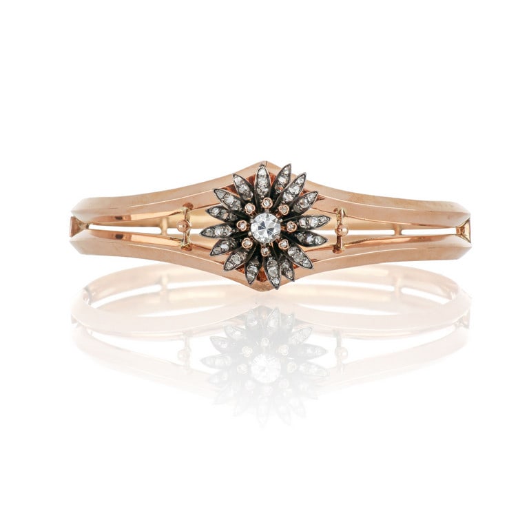 Bracciale rigido in oro rosso e argento,: Bracciale rigido in oro rosso e argento, realizzato in canna vuota, il motivo a due anelle parallele è disgiunto al centro e decorato con un fiore di piccoli diamanti taglio rosa, uno falso al ce