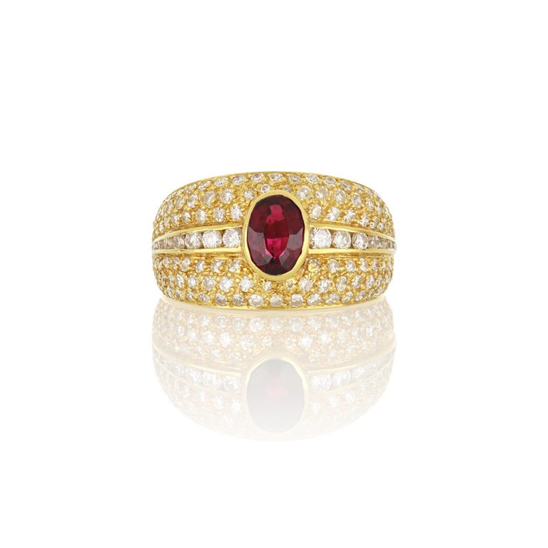 Anello a fascia in oro giallo, al centro un: Anello a fascia in oro giallo, al centro un vivido rubino taglio ovale di ct. 0,80 ca., diamanti taglio brillante e 8/8 tempestano la superficie. Misura n. 9. Peso 7,98 g.