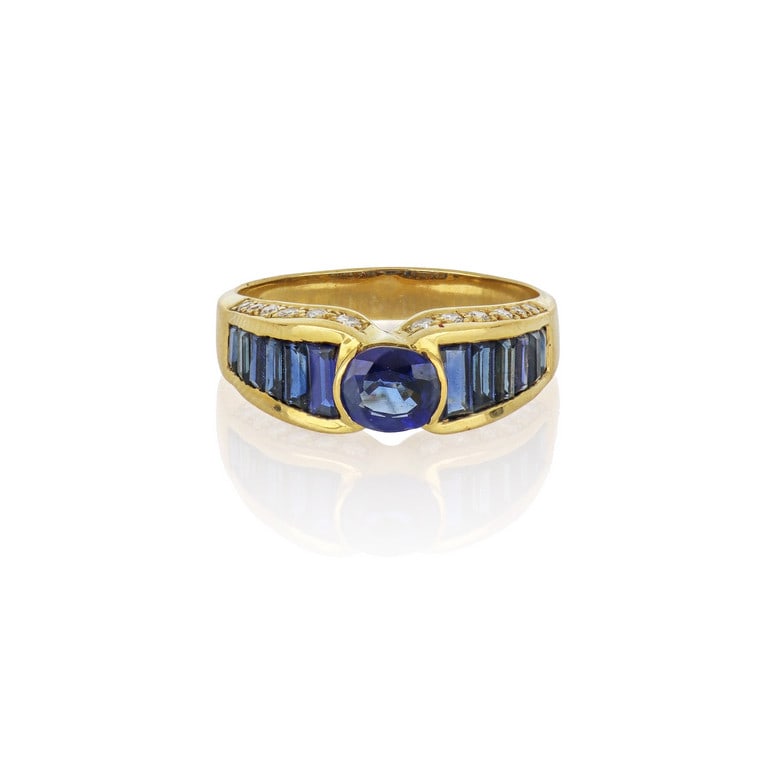 Anello in oro giallo, uno zaffiro taglio ovale è: Anello in oro giallo, uno zaffiro taglio ovale è qui accompagnato da una scaletta di zaffiri taglio baguette sul gambo a scalare, piccoli diamanti taglio brillante incassati sui due lati. Misura 