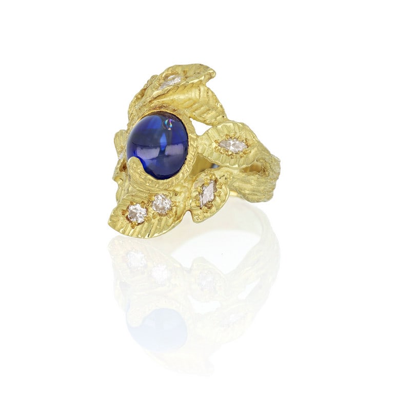 Grande anello in oro giallo con lavorazione: Grande anello in oro giallo con lavorazione "Sforza" a fogliame, al centro una bacca stilizzata con un elegante zaffiro taglio cabochon rotondo di ct. 3,00 ca., ai lati sulle foglie diamanti di divers