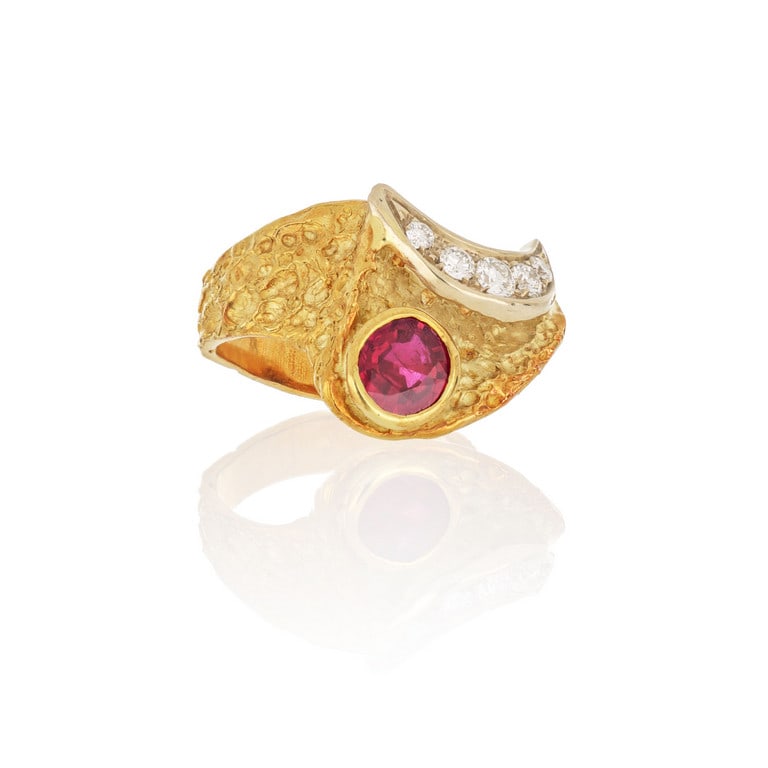 Grande anello in oro giallo con lavorazione a: Grande anello in oro giallo con lavorazione a corteccia, la forma fantasiosa è decorata con un fine e luminoso rubino taglio ovale di ct. 2,00 ca. e 5 piccoli diamanti taglio brillante di ct. 0,5