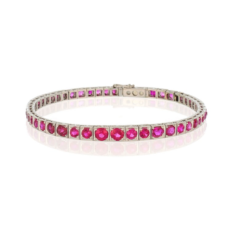 Elegante bracciale in oro bianco a "Tennis", 50: Elegante bracciale in oro bianco a "Tennis", 50 rubini, in parte sintetici, si rincorrono al polso di questo classico gioiello, finemente inciso e realizzato a scalare dalla parte centrale ai lati. Lu