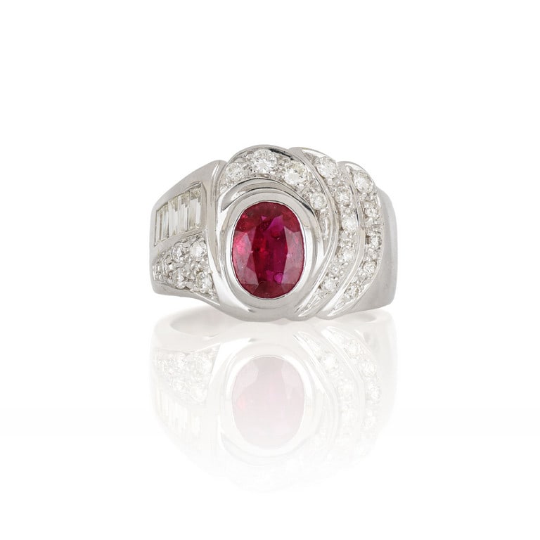 Anello in oro bianco a fascia, il decoro: Anello in oro bianco a fascia, il decoro asimmetrico è realizzato con piccoli diamanti taglio brillante e baguette, ct. 1,00 ca., al centro un rubino taglio ovale di ct. 1,50 ca. Misura n. 9. Pes