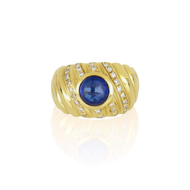 CUSI Anello a fascia in oro giallo con zaffiro: CUSI Anello a fascia in oro giallo con zaffiro cabochon a base tonda di stimati 2,80 ct, rifiniscono la decorazione 0,28 ct di diamanti. Misura 16. Peso 11,68 g.